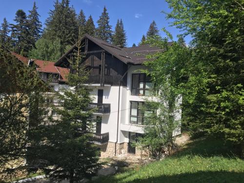 a large white building in the middle of trees at Montana Residence in Poiana Brasov