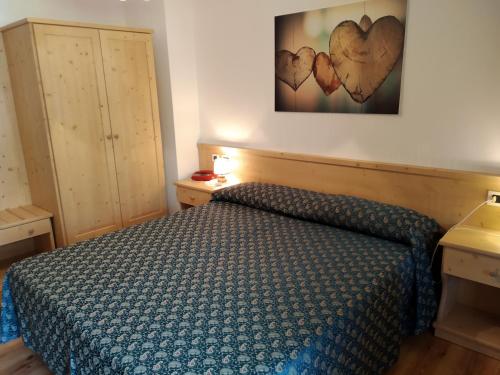 a bedroom with a bed and two hearts on the wall at Hotel Garnì Miramonti in Falcade