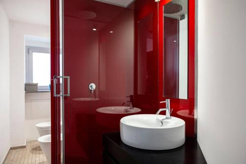 uma casa de banho com um lavatório branco e paredes vermelhas em Cortile Vittorio Charme em Catânia