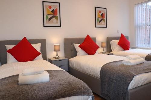 a bedroom with two beds with red and white pillows at Modern Newgate Apartments - Convenient Location, Close to All Local Amenities in Stoke on Trent