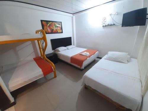 a small room with two beds and a tv at Hotel Arcoiris Girardot in Girardot
