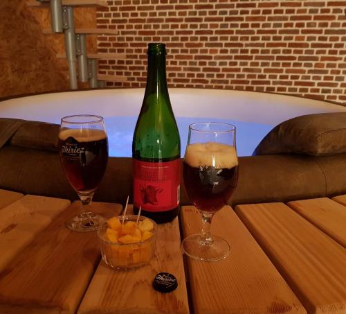 a bottle of wine and two glasses on a table at Odyssée - Chambre d'hôtes avec spa et sauna privés in Zeggers-Cappel