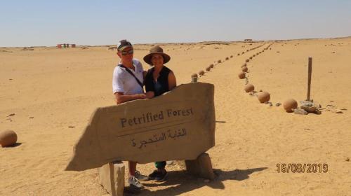 a man and woman standing next to a sign in the desert at H100 Pyramids View in Giza