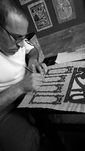 a man sitting at a table writing on a sign at H100 Pyramids View in Giza