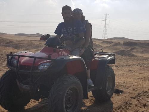 three people sitting on the back of a four wheeler in the desert at H100 Pyramids View in Giza