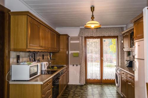 a kitchen with wooden cabinets and a white microwave at Ferienwohnungen Angermaier in Flattach