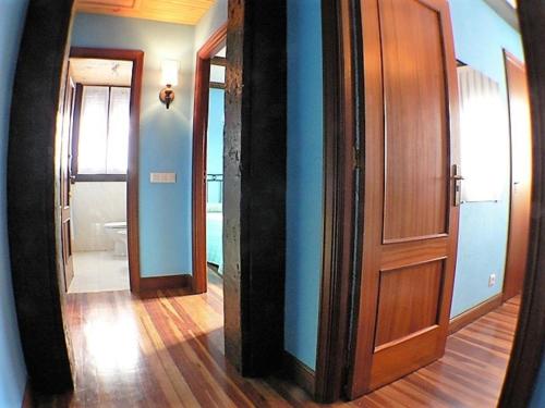 a hallway with a wooden door and a mirror at Casa Rural Arboliz in Ibarrangelu