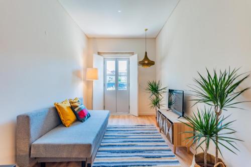 een woonkamer met een blauwe bank en een aantal planten bij Boavista Garden Apartment in Porto