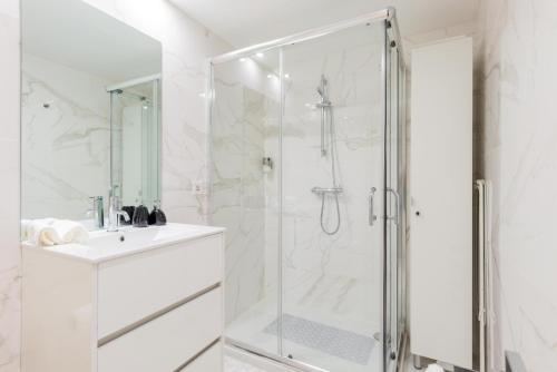 een witte badkamer met douche en wastafel bij Boavista Garden Apartment in Porto