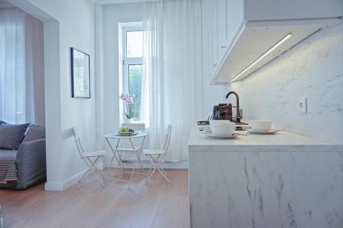 a white kitchen with a counter and a table at Apartament Jola in Sopot