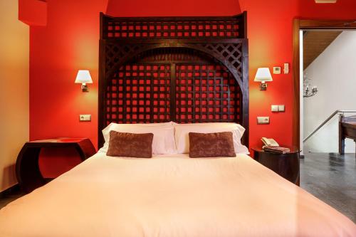 a bedroom with a large bed with red walls at Eco Hotel Boutique & Spa Capitulo Trece - Adults Only in Maderuelo
