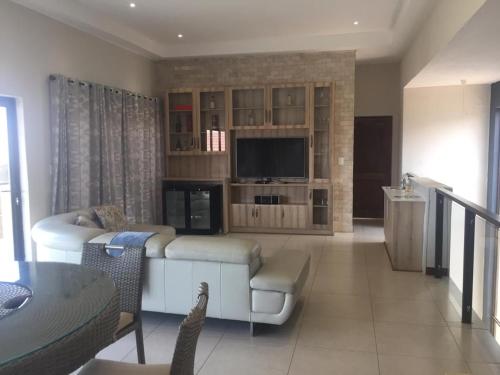 a living room with a couch and a television at Bluewave Lifestyle Villa in Hartbeespoort