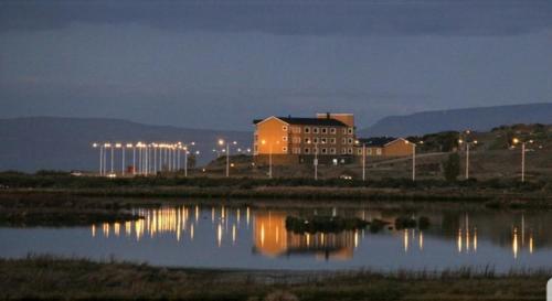 a building with its lights on next to a body of water at Hotel Las Dunas in El Calafate