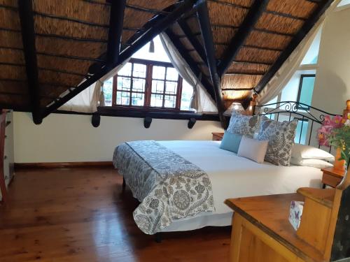 ein Schlafzimmer mit einem großen Bett in einem Zimmer mit Fenstern in der Unterkunft Little Tree loft 2 in Uitenhage