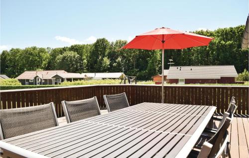 a wooden table with a red umbrella on a deck at Holiday Home Pøt Strandby Juelsminde Q in Sønderby