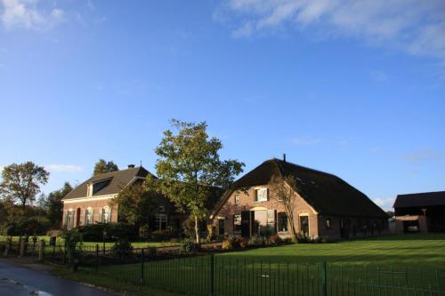 une maison avec un toit noir et une cour gazonnée dans l'établissement De Aze, à Terwolde