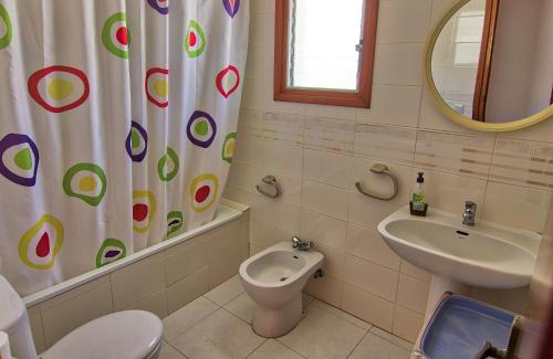 Un baño con lavabo, inodoro y cortina de ducha. en Casa Albina, en Riumar