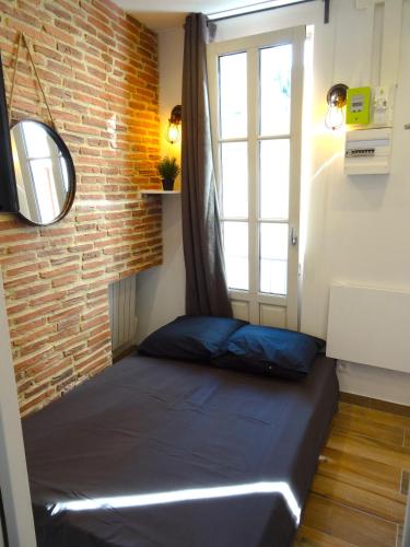 un lit dans une chambre avec un mur de briques dans l'établissement ★★★Studio Heart of Le Marais, Design Flat★★★, à Paris