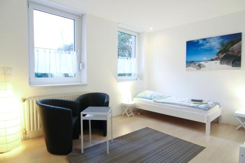 a room with a bed and a chair and two windows at apartmondo Apartmentwohnungen Remscheid in Remscheid