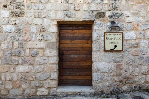 a stone building with a wooden door with a sign on it at Eco Hotel Boutique & Spa Capitulo Trece - Adults Only in Maderuelo