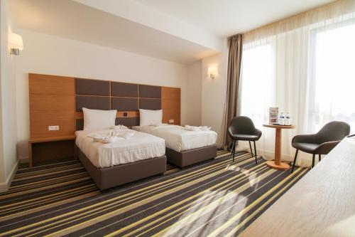 um quarto de hotel com duas camas e uma mesa e cadeiras em Hotel Avenue - Avenue Hotels em Buzău