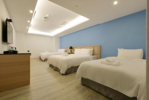 a hotel room with three beds and a television at Hotel Champs Elysées in Taichung