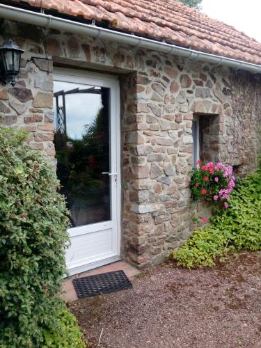 a stone house with a white door and flowers at Domaine du mont scolan in Montgardon