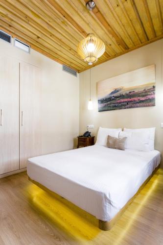 a large white bed in a bedroom with a wooden ceiling at Blossom rooms & suite in Veria