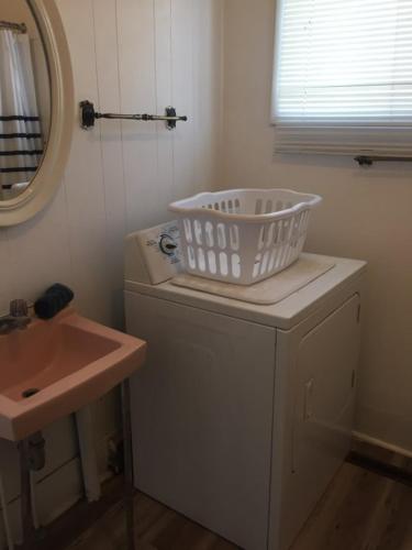 a bathroom with a sink and a laundry basket on a washing machine at Cozy Cottage in Canora