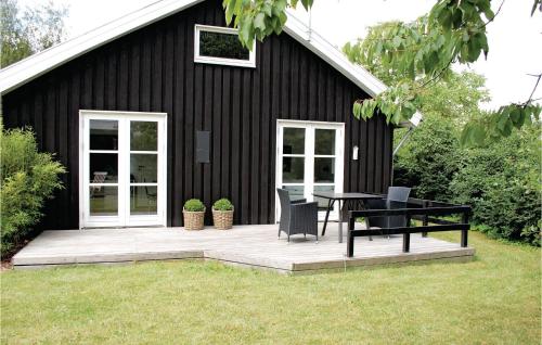 a black house with a picnic table and chairs on a deck at Holiday Home Havhusevej Hornslet Denm in Hornslet