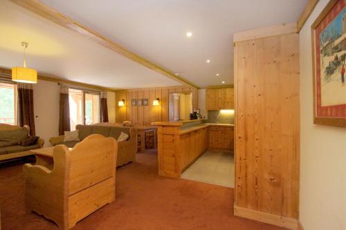Il comprend une cuisine et un salon avec des placards en bois et un canapé. dans l'établissement Bel appartement 6 à 8 personnes au pied des pistes, à Les Deux Alpes