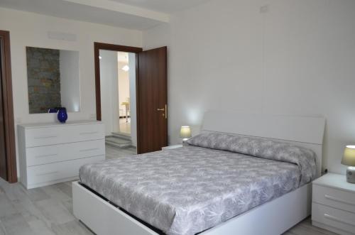 una camera bianca con un grande letto e uno specchio di B&B da Palminio a Loceri