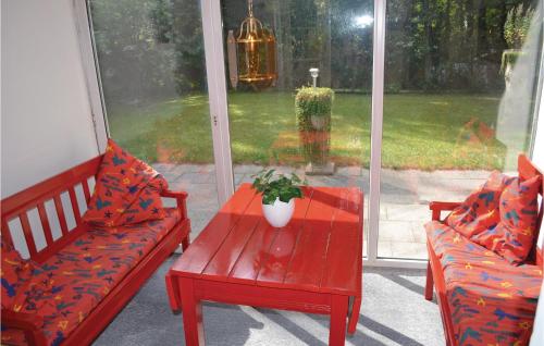 Un porche con dos bancos rojos y una mesa con una planta. en Solhytten, en Bøtø By