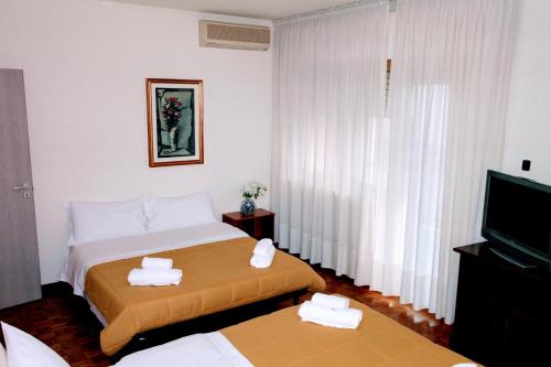 a hotel room with two beds and a television at Rosa Garden B&B in Mestre