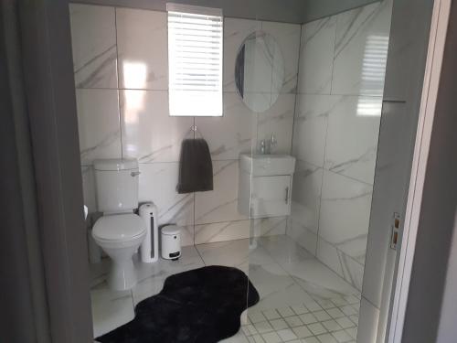 a white bathroom with a toilet and a mirror at ikibiki in Beaufort West