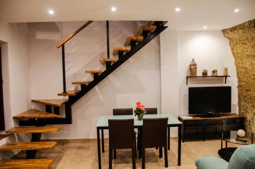 a living room with a table and a tv and stairs at Casa Cueva El Arrabal in Setenil
