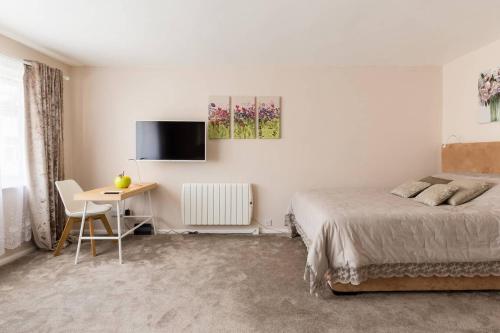 a bedroom with a bed and a desk and a tv at Chocolate Nest in Leamington Spa