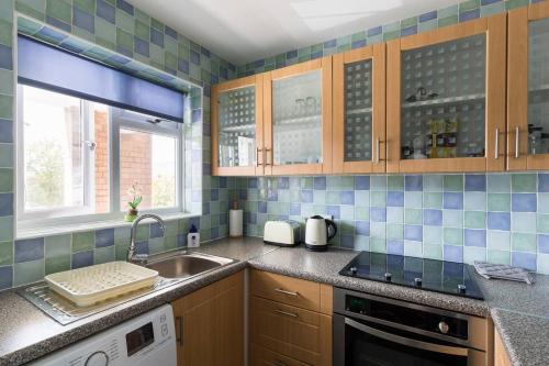 a kitchen with blue tiled walls and a sink at Chocolate Nest in Leamington Spa
