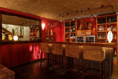 un bar con sillas y una pared roja en Eco Hotel Boutique & Spa Capitulo Trece - Adults Only, en Maderuelo