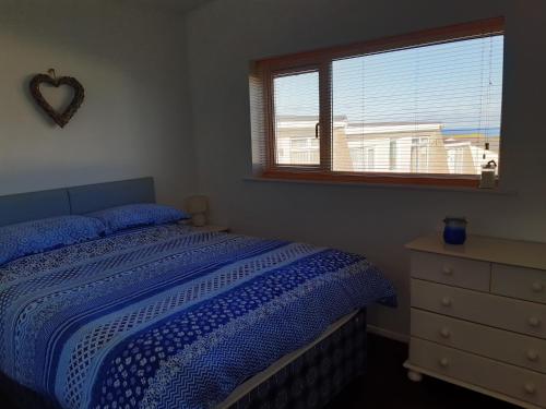 a bedroom with a bed and a window and a dresser at Chalet 18 Widemouth Bay Holiday Village in Bude