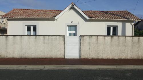 a white house behind a fence at La Maison du Pontac in Villenave-dʼOrnon