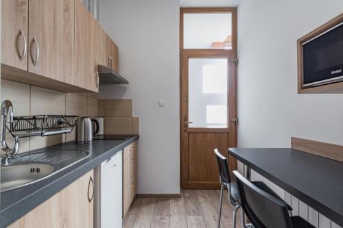 a kitchen with a sink and a counter with chairs at Apartamenty INTERDOM in Zakopane