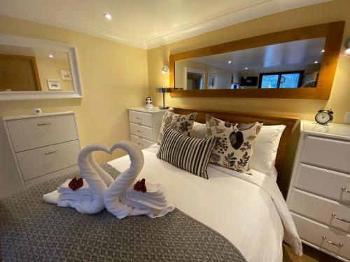 dos cisnes hechos de toallas sentadas en una cama en The Wee Ludging Cottage, Rashfield, by Dunoon en Dunoon