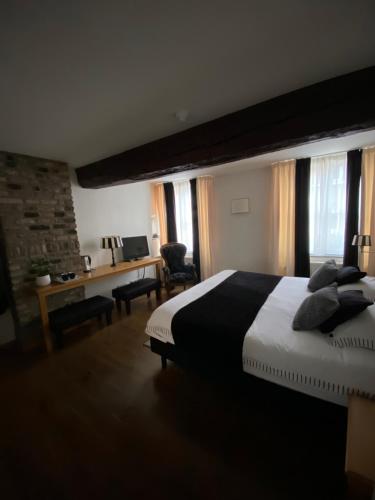 a bedroom with a large bed with a desk and windows at Chambres D'Hotes Rekko in Maastricht