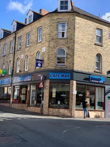 a brick building on a street with a person walking in front at Cotswold Valley Aparthotel in Stroud