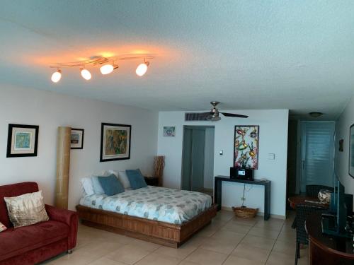 1 dormitorio con 1 cama y 1 sofá rojo en Cond. Marina Lanais, en Fajardo