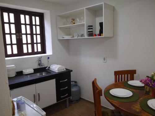 a kitchen and dining room with a table and a sink at Chalé Topázio in Monte Verde