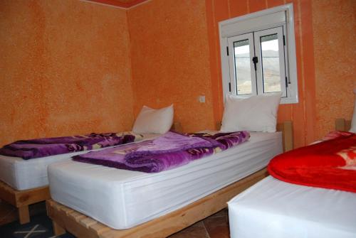 - 2 lits dans une chambre avec fenêtre dans l'établissement Auberge Tafilalt Bouzmou Bouzmou, à Imilchil