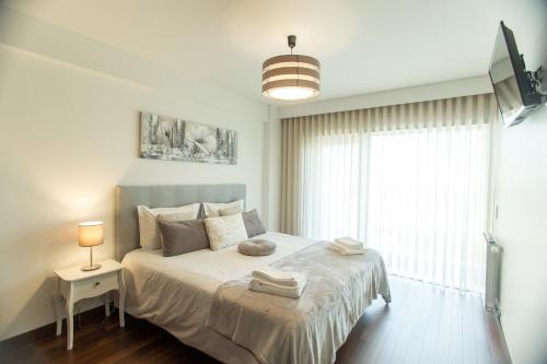 a white bedroom with a bed and a window at Afurada premium apartment by Porto City Hosts in Vila Nova de Gaia