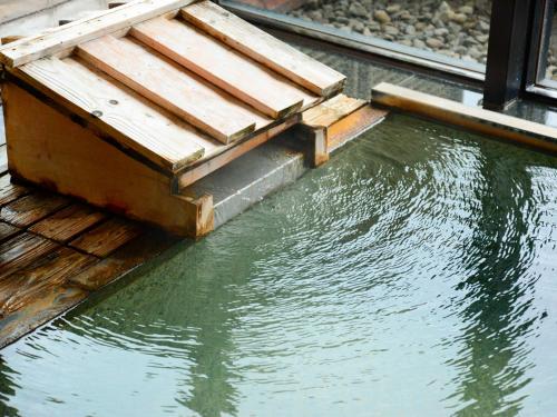 a pool of water next to a wooden deck at Hanamomiji in Jozankei